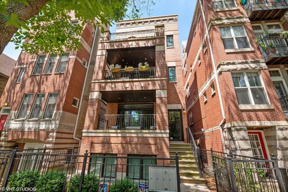 Front view of a multi-story brick apartment building with balconies.