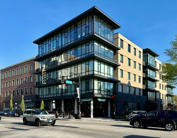 Front view of a modern multi-story building with glass windows and brick exterior.
