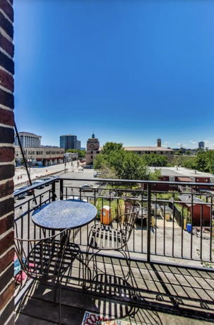 View from a balcony overlooking a cityscape with buildings and trees.