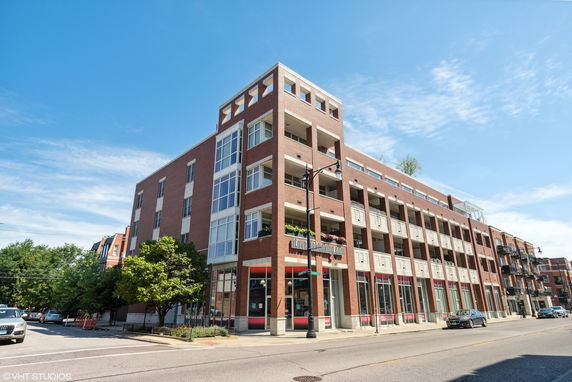 Front view of a multi-story brick building with large windows and balconies.