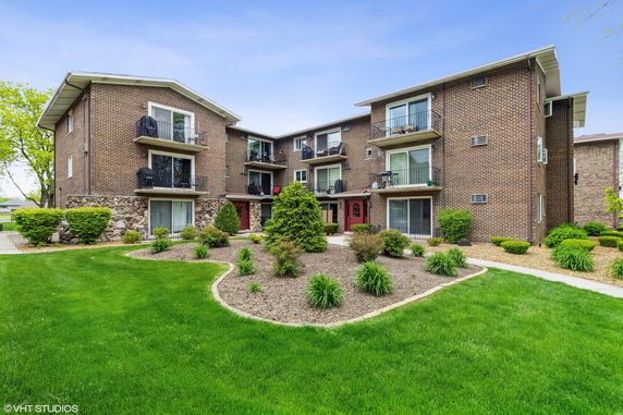 Front view of a multi-story brick apartment building with balconies.