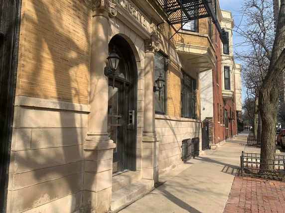 Front view of a brick building entrance with decorative columns.