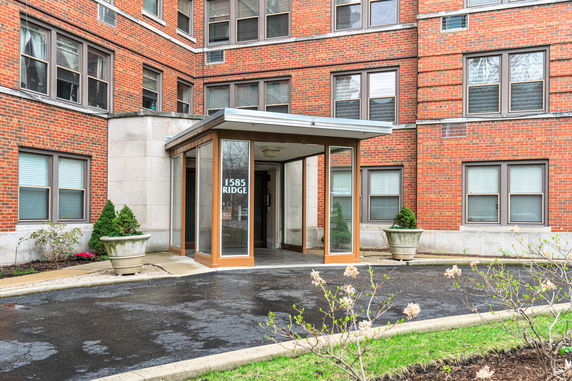 Entrance of a brick apartment building with large windows.