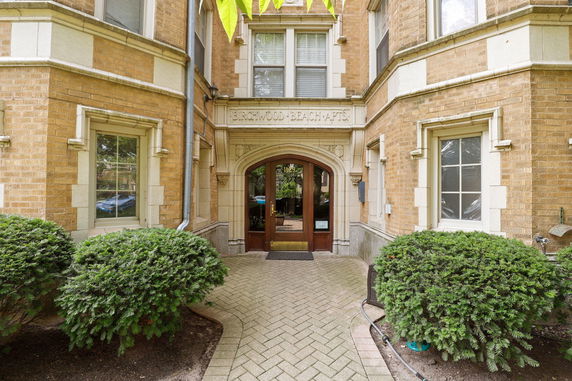 Front view of an apartment building entrance with brick exterior and arched doorway.