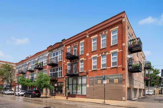 Front view of a three-story brick apartment building with multiple balconies.
