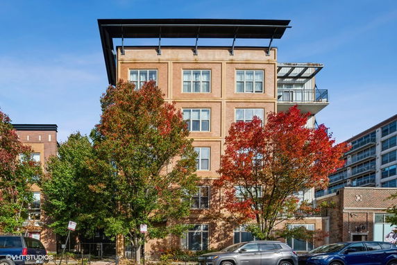 Front view of a multi-story brick building with balconies and a large rooftop structure.