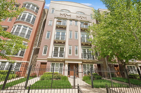 Front view of a multi-story building with balconies and green landscaping.