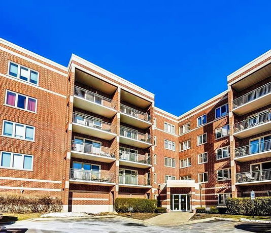 Front view of a multi-story brick apartment building with balconies.
