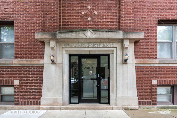 Front view of an apartment building with a brick exterior and entrance door.
