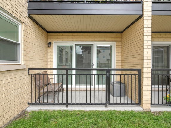 Front view of a building with a balcony and sliding glass doors.