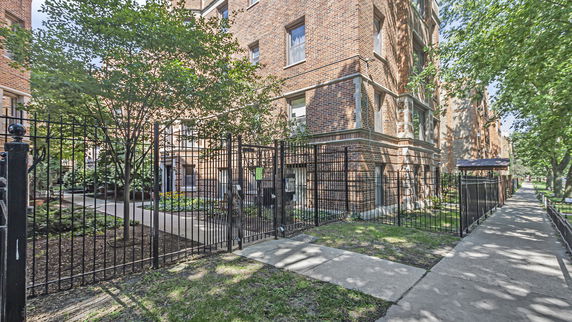 Front view of a multi-story brick building with fenced entrance.
