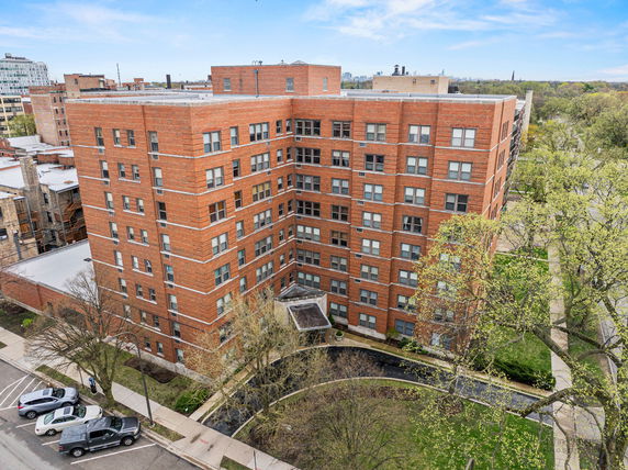 Aerial view of a multi-story brick building with multiple windows and a small entrance canopy.