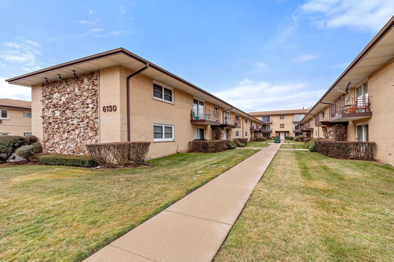 Front view of apartment buildings with balconies and a pathway.