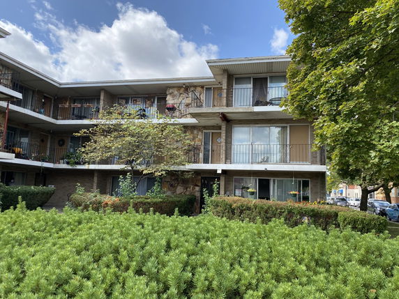 Front view of a three-story apartment building with balconies.
