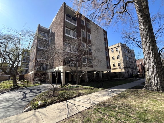 Front view of a multi-story brick apartment building with balconies.