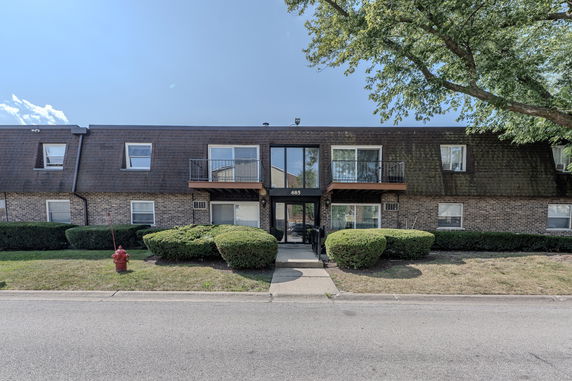 Front view of a two-story residential building with balconies and a flat roof.