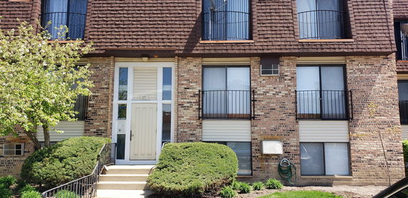 Front view of a multi-story residential building with brick facade and balconies.