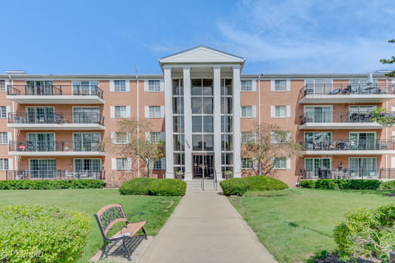 Front view of a multi-story brick apartment building with balconies.
