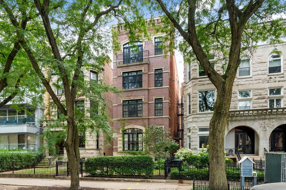 Front view of a multi-story brick residential building with large windows.
