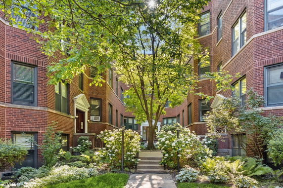 Front view of a multi-story brick apartment building with a courtyard.