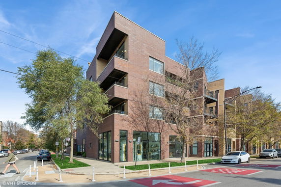 Front view of a modern, multi-story brick building on a street corner.