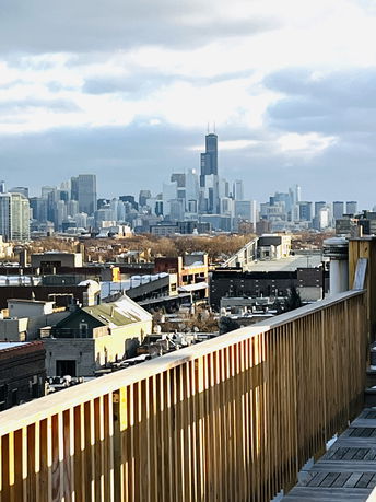 Panoramic view of a city skyline with a wooden railing in the foreground.