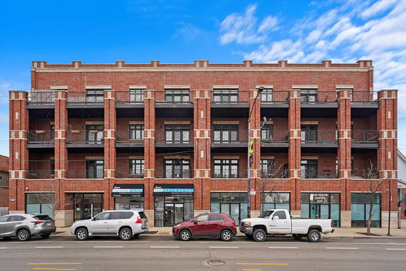 Front view of a multi-story brick apartment building with balconies.