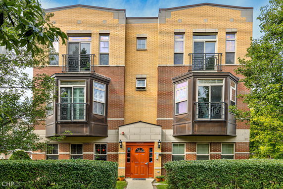 Front view of a multi-story brick building with bay windows and a central entrance.