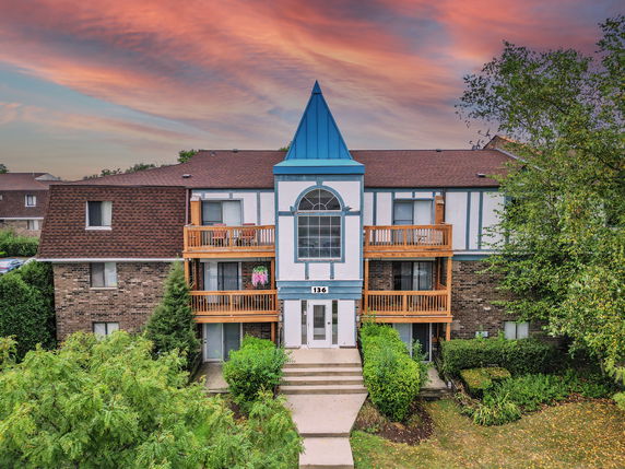 Front view of a multi-story building with a blue triangular roof section and wooden balconies.