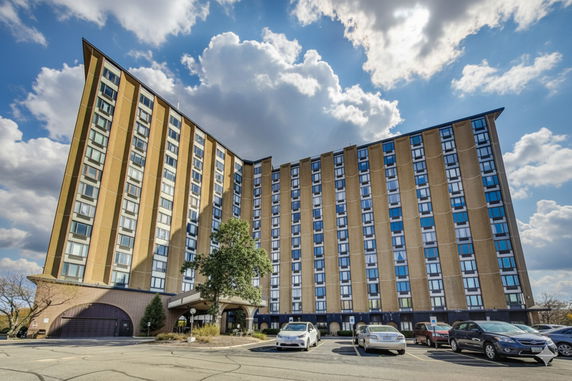 Front view of a multi-story residential building with parking area.