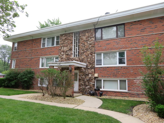 Front view of a three-story brick apartment building with stone accents.