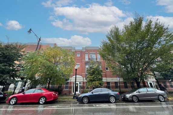 Front view of a multi-story brick building with multiple windows and small balconies.