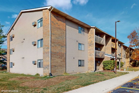 Front view of a three-story apartment building with brick and siding exterior.