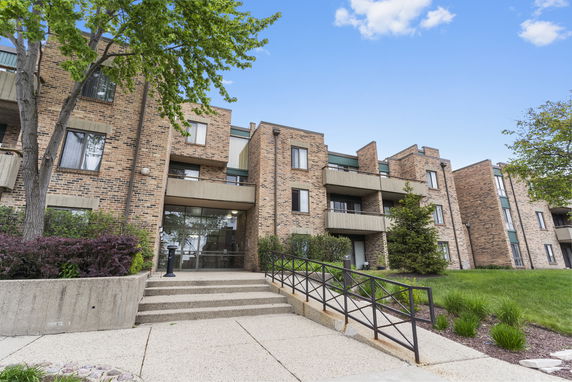 Front view of a multi-story apartment building with brick facade and balconies.
