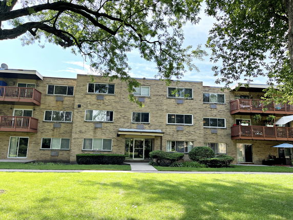Front view of a three-story brick apartment building with balconies.