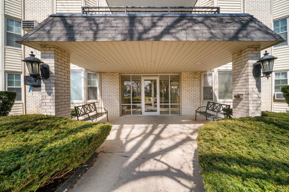 Front view of a building entrance with a covered porch and glass doors.