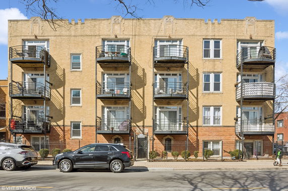 Front view of a multi-story brick apartment building with balconies.