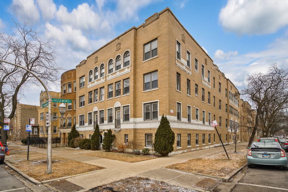 Front view of a multi-story brick apartment building on a street corner.