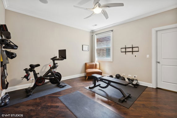 Indoor home gym with exercise bike and bench.