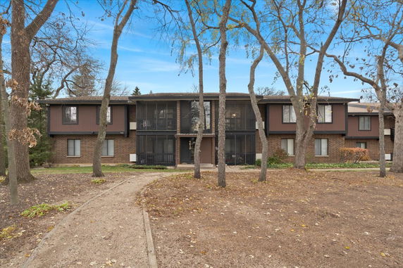 Front view of a two-story apartment building with brown brick and wood paneling.