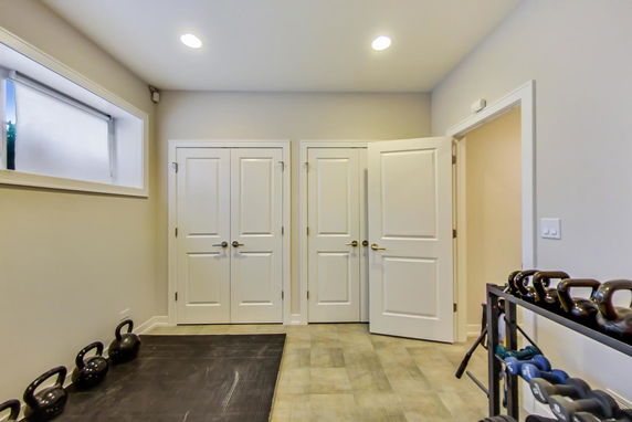 Room with gym equipment including kettlebells and weights.