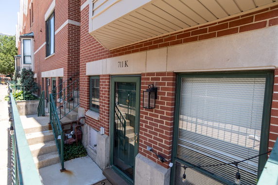 Front view of a brick building entrance with steps leading to the door.