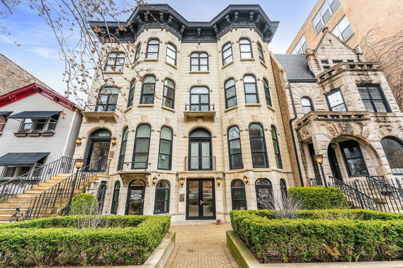 Front view of a multi-story historic building with large arched windows and decorative stonework.