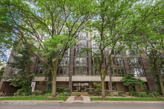 Front view of a multi-story building with large windows and surrounding trees.