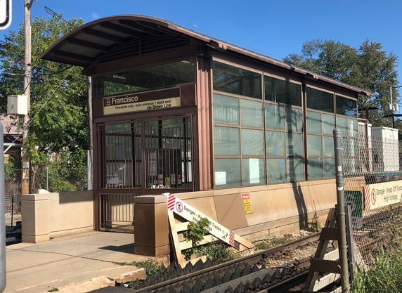 Front view of a railway station entrance with a modern glass and metal structure.
