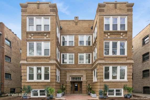 Front view of a multi-story brick building with symmetrical design and white framed windows.