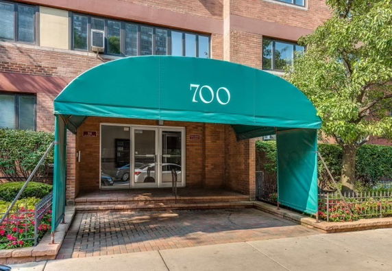 Front view of a building entrance with a green awning displaying the number 700.