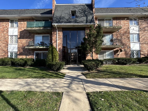 Front view of a multi-story brick apartment building with balconies.