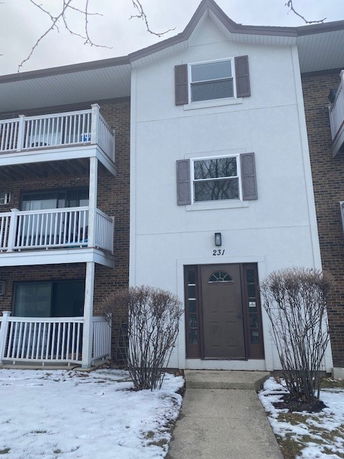 Front view of a three-story residential building with balconies and a central entrance.