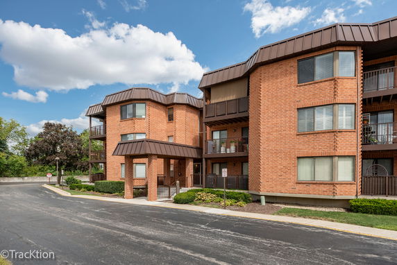 Front view of a brick multi-story residential building with balconies.